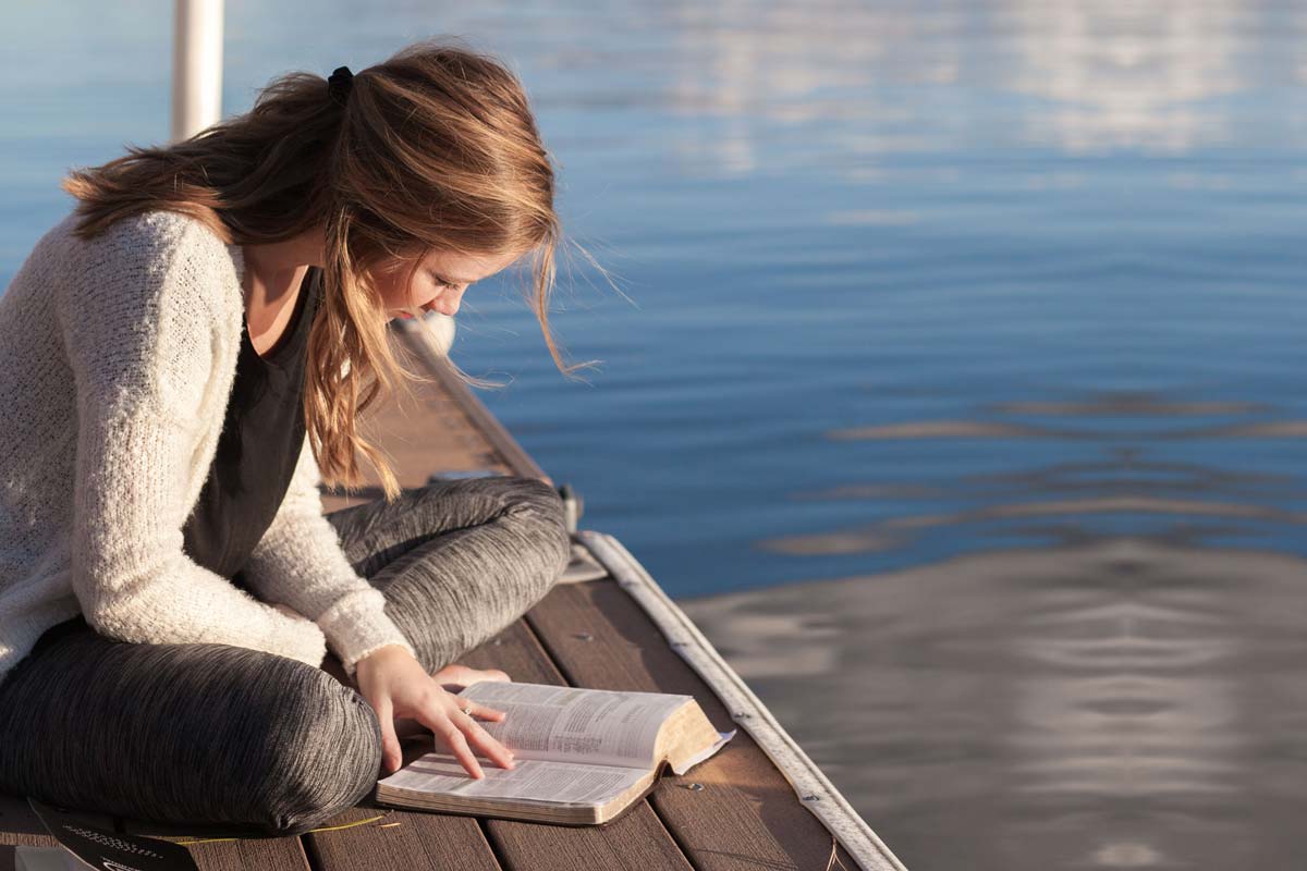image of a woman reading on a dock